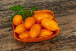 Yellow tomato heap in the wooden bowl photo