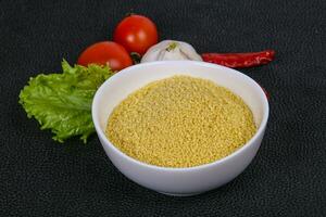 Raw couscous in the bowl served salad leaves, tomato and pepper photo