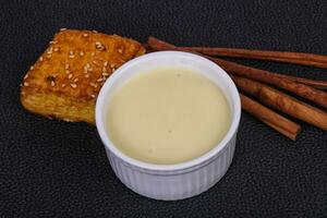 Condenced milk in the bowl with sinnamon and pastry photo