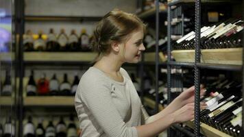 jovem mulher é escolhendo vinho dentro a supermercado video