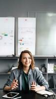 un sofisticado mujer de negocios es atractivo en un vídeo conferencia desde su oficina o hogar. ella es atentamente mirando dentro el web cámara, articular su pensamientos y ideas con claridad y confianza. foto