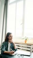 Young woman multitasking with laptop computer at office and student girl working remotely from home. Online work, study, freelance, and modern office lifestyle concept photo