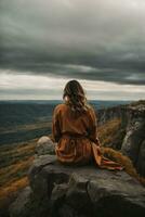 espalda ver de un mujer sentado solo a el grande montañas. ai generativo foto