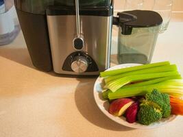 Juicer with plate of fresh vegetables photo