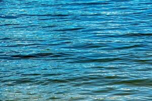 Water ripple texture background. Wavy water surface during sunset, golden light reflecting in the water. photo