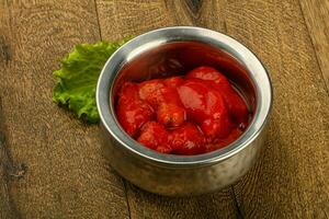 Peeled tomatoes over wooden background photo