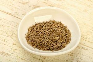 Cumin seeds over wooden background photo