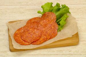 Pepperoni sausage over wooden background photo