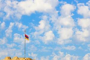 Armenian flag on pole with cross on top of hill photo