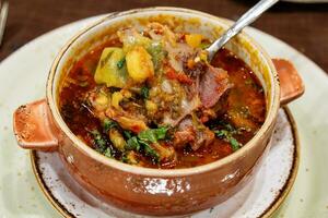 eating of traditional soup Chanakh in ceramic pot photo