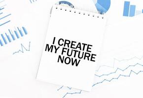 White notepad with text I CREATE MY FUTURE NOW on the financial documentation. Finance and business concept photo