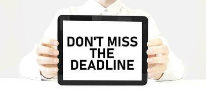 Text don't miss the deadline on tablet display in businessman hands on the white background. Business concept photo