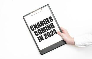 un empresario sostiene un carpeta con papel sábana con el texto cambios viniendo en 2024 . negocio concepto. foto