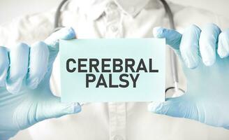 Doctor holding card in hands and pointing the word CEREBRAL PALSY photo