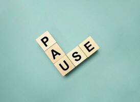 pause word on wooden block on green background photo