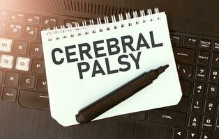 White paper sheet with text CEREBRAL PALSY on the black laptop photo