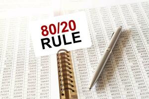 Text 80 and 20 rule on paper card, pen, financial documentation on table photo