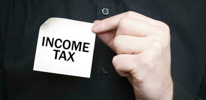 Businessman holding a card with text INCOME TAX, business concept photo