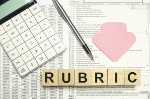 rubric words on wooden blocks with sticker, calculator and pen photo