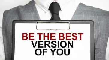 Businessman holding sheet of paper with a message BE THE BEST VERSION OF YOU photo