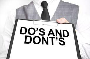 Businessman holding sheet of paper with a message DO's and DONT's photo