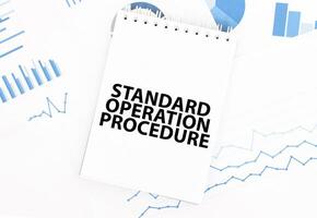 White notepad with text STANDARD OPERATION PROCEDURE on the financial documentation. Finance and business concept photo