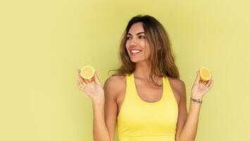 Beautiful  woman posing over  green background , holding fresh  lemons.  Beauty studio portrait. Healthy life style. photo