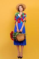 bonito europeo mujer en azul vestir participación ramo de flores de flores terminado amarillo antecedentes. Paja sombrero. verano humor. foto