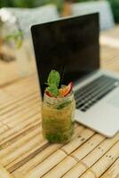 Lap top and mojito on table. photo