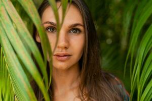 cerca agraciado mujer modelo en rojo nadar vestir con largo Derecho pelo posando en tropical naturaleza. foto