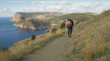 Mann mit schwer groß Rucksack und Wandern Stangen hat Trekking video