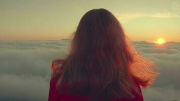 Lonely woman is standing on top of mountain above clouds. Instagram look. video