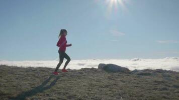 joven caucásico mujer en Gafas de sol es trotar en montañas. lado vista. video