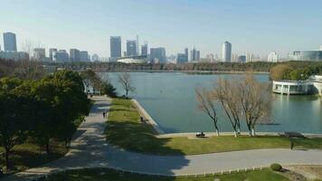 siglo parque con un grande lago en llevar a la fuerza a soleado día. céntrico a antecedentes. porcelana. aéreo vista. zumbido es volador adelante y hacia arriba. estableciendo Disparo video