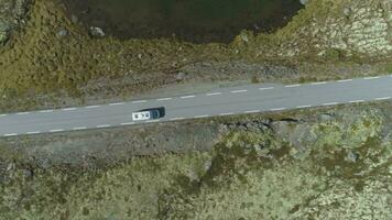 branco motorhome carro é indo em montanha estrada dentro Noruega às verão ensolarado dia. aéreo vertical Careca visualizar. zangão é vôo lateralmente video