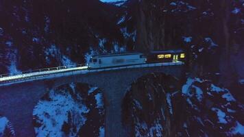 landwasser viaduc avec chemin de fer et train à hiver soir. montagnes, forêt et rivière. aérien voir. Suisse vieux pont et la nature. drone mouches en arrière et vers le haut video