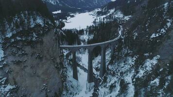 Landwasser Viadukt mit Eisenbahn beim Winter Tag. Berge und Wald. schweizerisch Alpen. Antenne Sicht. Drohne fliegt nach vorne, Kamera kippt oben video