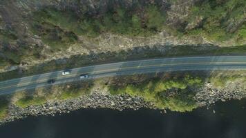Autos sind gehen auf Land Straße in der Nähe von See im Norwegen im Sommer- sonnig Tag. Antenne Vertikale von oben nach unten Sicht. Drohne ist fliegend seitwärts video