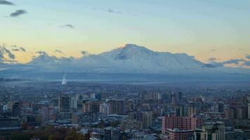 Tempo lapso do Yerevan cidade e coberto de neve montar ararat em fundo às nascer do sol. comovente nuvens. video