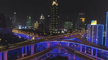 Yan'an elevado estrada ultrapassar às noite com azul iluminação e Xangai paisagem urbana. China. aéreo visualizar. zangão é vôo para trás e para cima. estabelecendo tomada. video