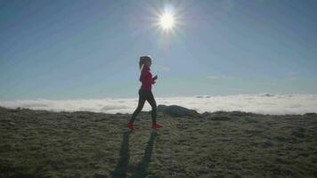 Frau ist Joggen im Berge über Wolke. schleppend Bewegung. Seite Sicht. video