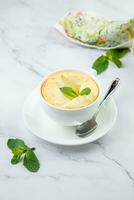 cup of coffee with foam and a sprig of mint on a marble background photo