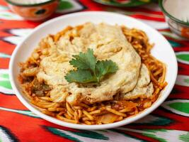 The oriental lagman dish is homemade noodles fried with meat, vegetables and herbs. Eastern cuisine photo