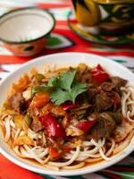 The oriental lagman dish is homemade noodles fried with meat, vegetables and herbs. Eastern cuisine photo