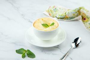 cup of coffee with foam and a sprig of mint on a marble background photo