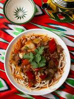 The oriental lagman dish is homemade noodles fried with meat, vegetables and herbs. Eastern cuisine photo