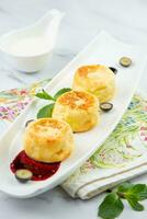 lush and tall cheesecakes with jam and mint on a white plate side view photo