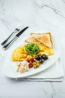 desayuno de huevos con carne, hierbas y gotas de salsa con un pan en un redondo plato foto