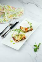 canapes on black bread with cheese, red fish, herbs and cucumber side view photo