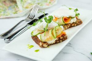 canapes on black bread with cheese, red fish, herbs and cucumber side view photo